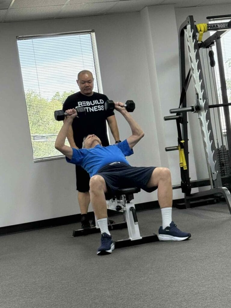 Man lifting dumbbells under coach guidance